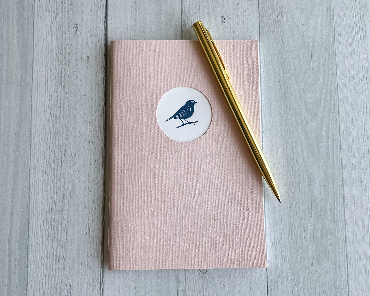 Signature Mini handbound journal in Petal pink linen textured cardstock with circular logo window.