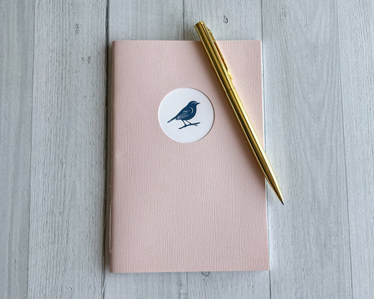 Signature Mini handbound journal in Petal pink linen textured cardstock with circular logo window.